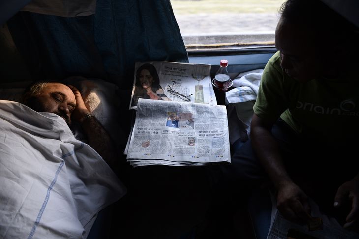 Un homme dort dans un compartiment de première classe. Sur la tablette, des journaux sur les élections législatives.